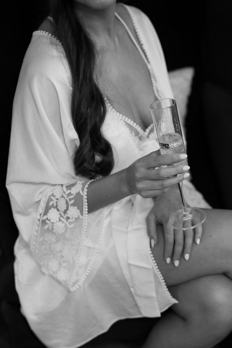 a woman wearing a white robe is sitting and holding a glass of champagne