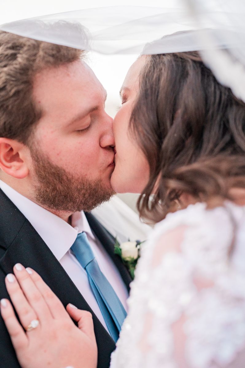 a copule kissing each other underneath the bride's veil
