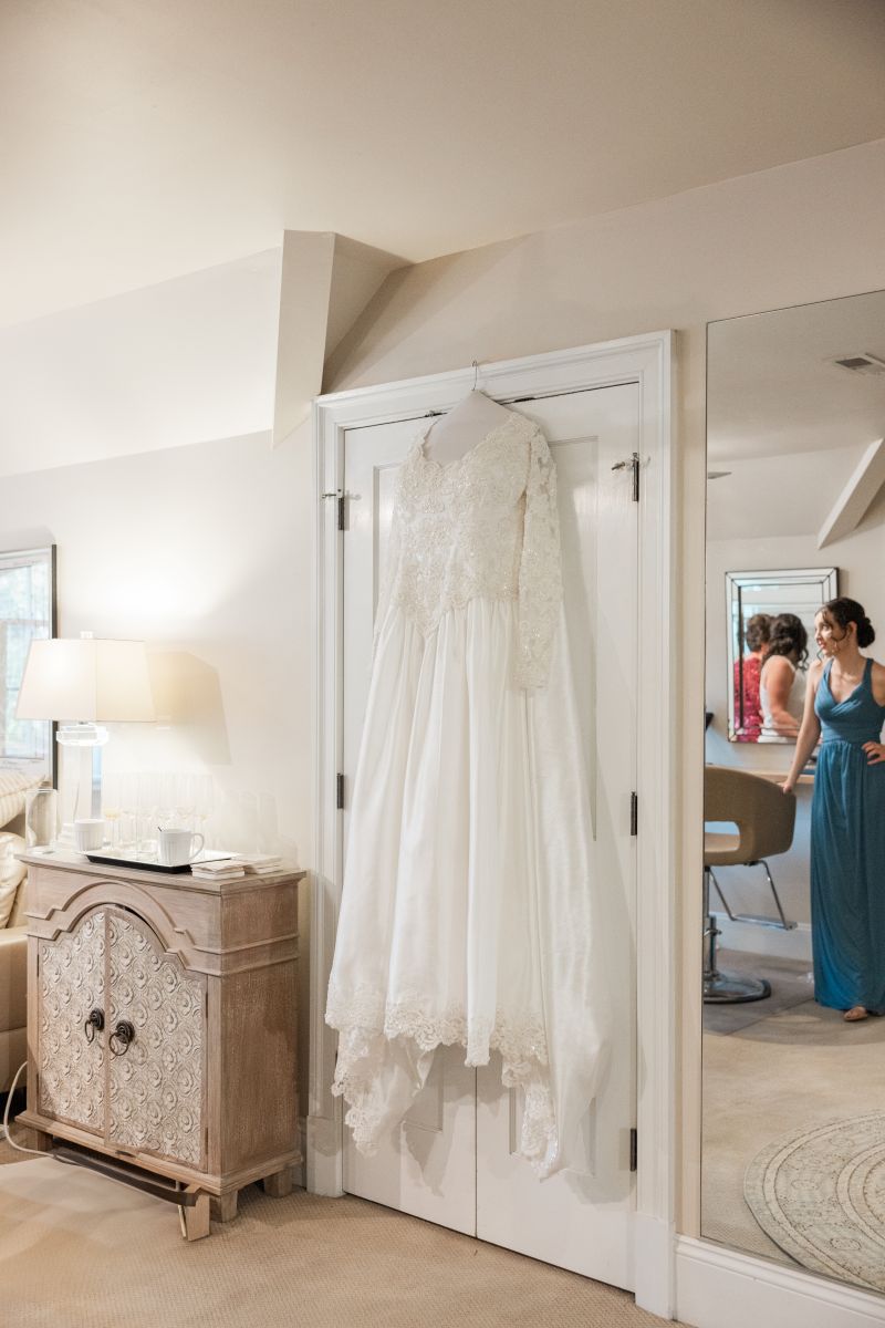 a white wedding dress in a getting ready room hanging on the back of a door