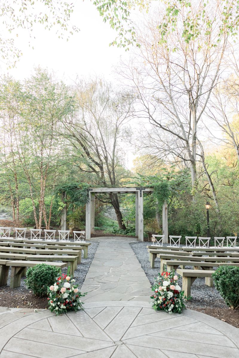 a ceremony site with a wooden arch and wooden benches set up for awedding