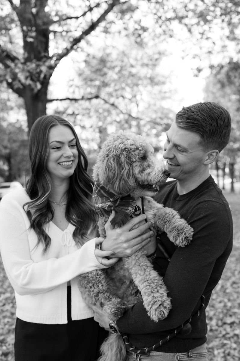 a couple lovingly holding their dog in their arms and smiling at their dog