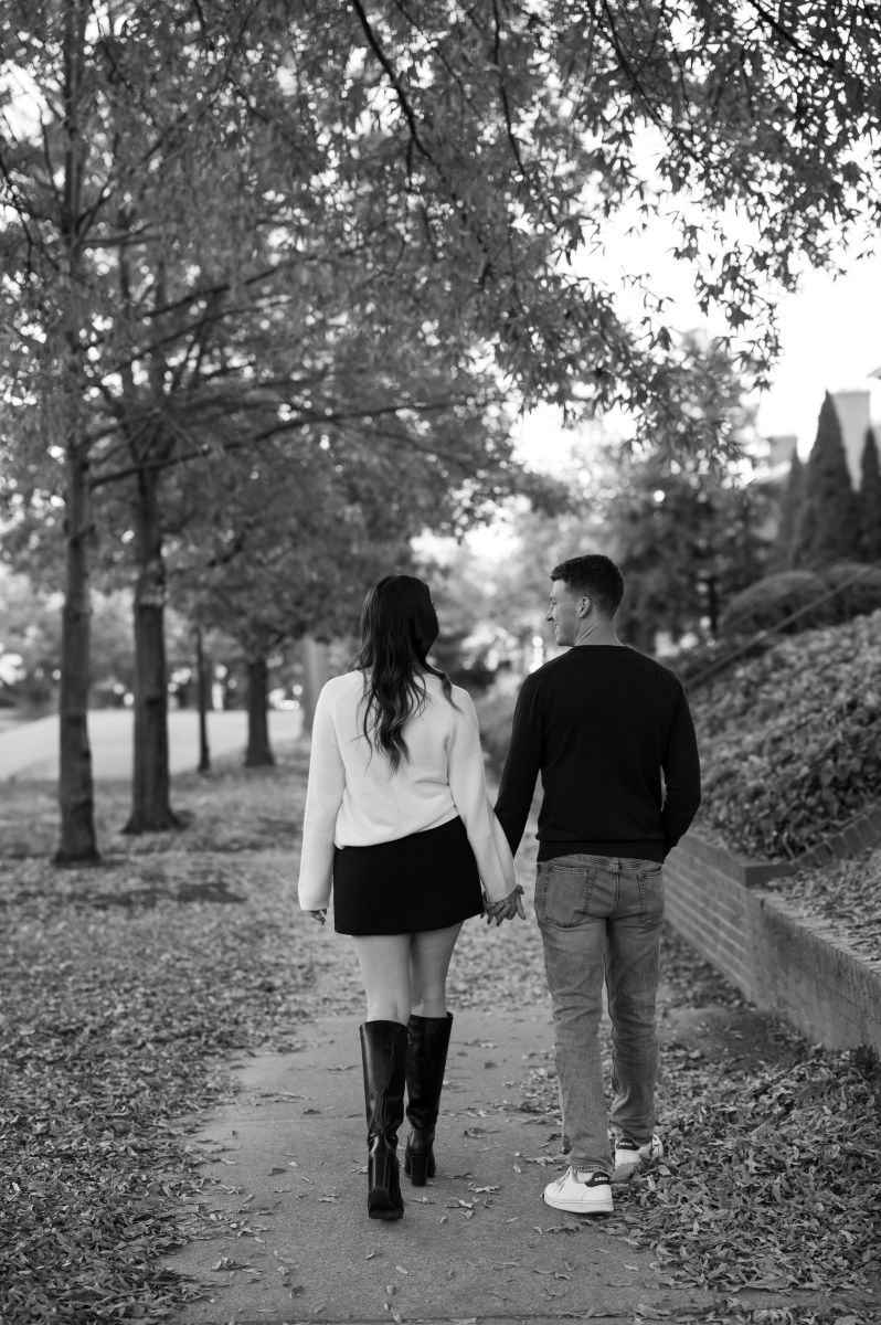 a couple walking down monument avenue in richmond viriginia surrounded by leaves, trees, and houses