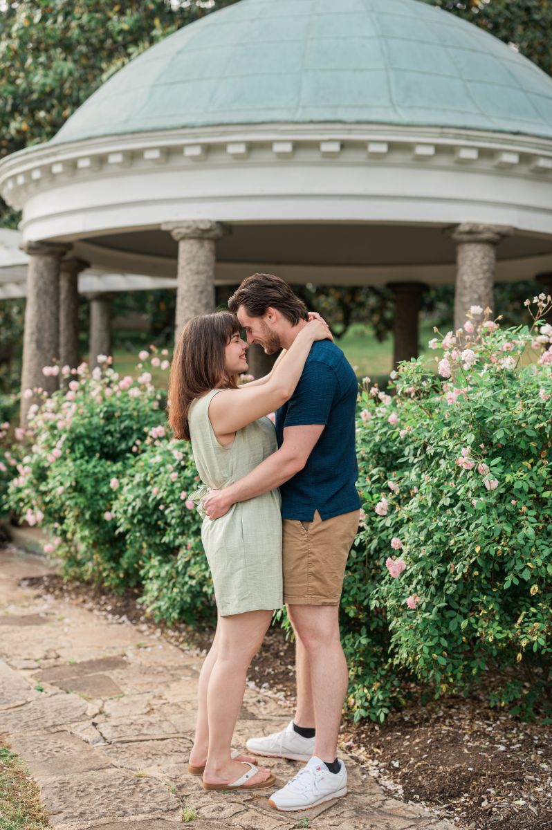 a couple in front of a pavilion at maymont park in virgina taking engagement photos they are embracing and smiling at each other