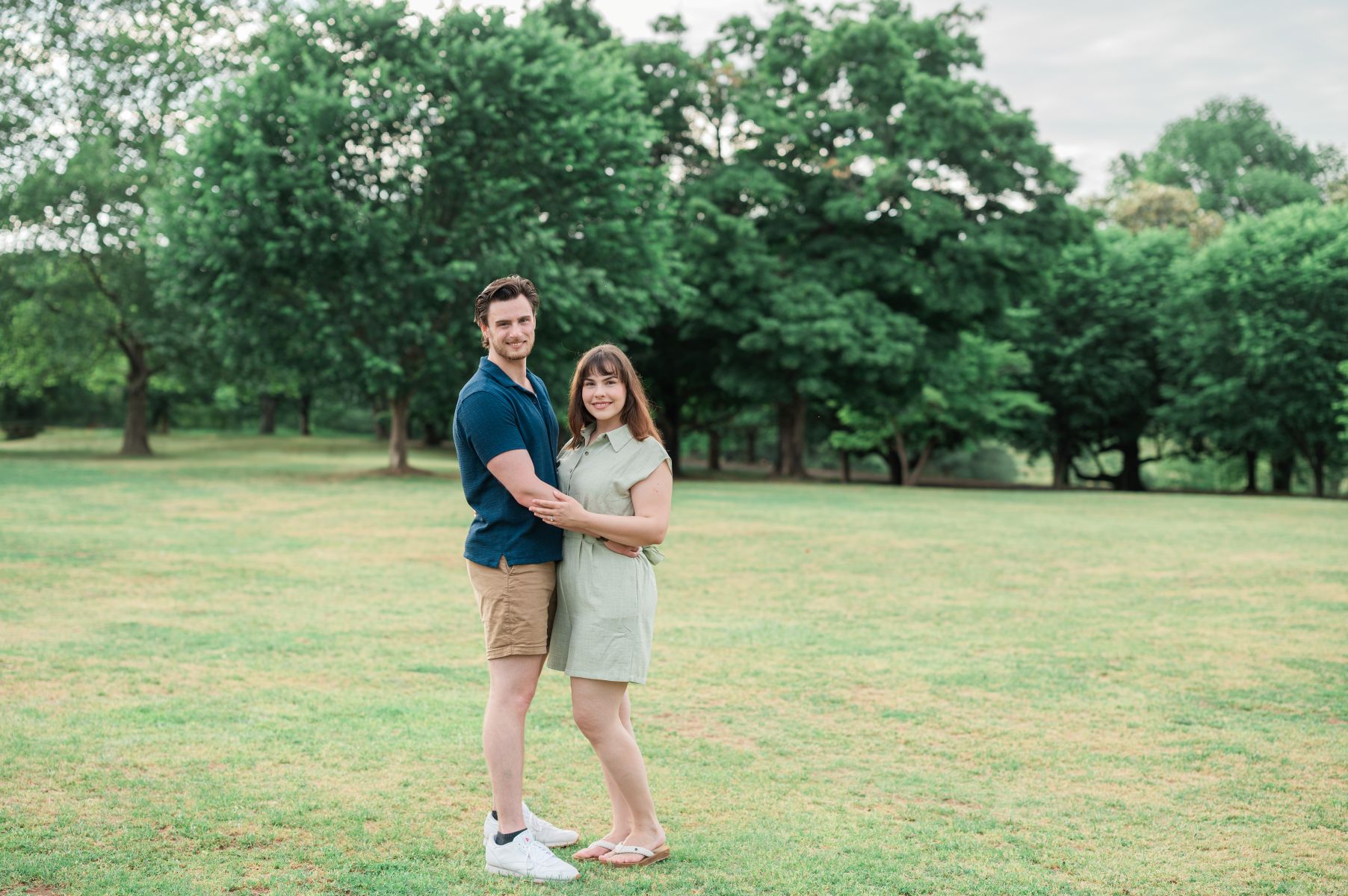 a couple taking engagement photos on the lawn at maymont park in virginia they are hugging each other and smiling