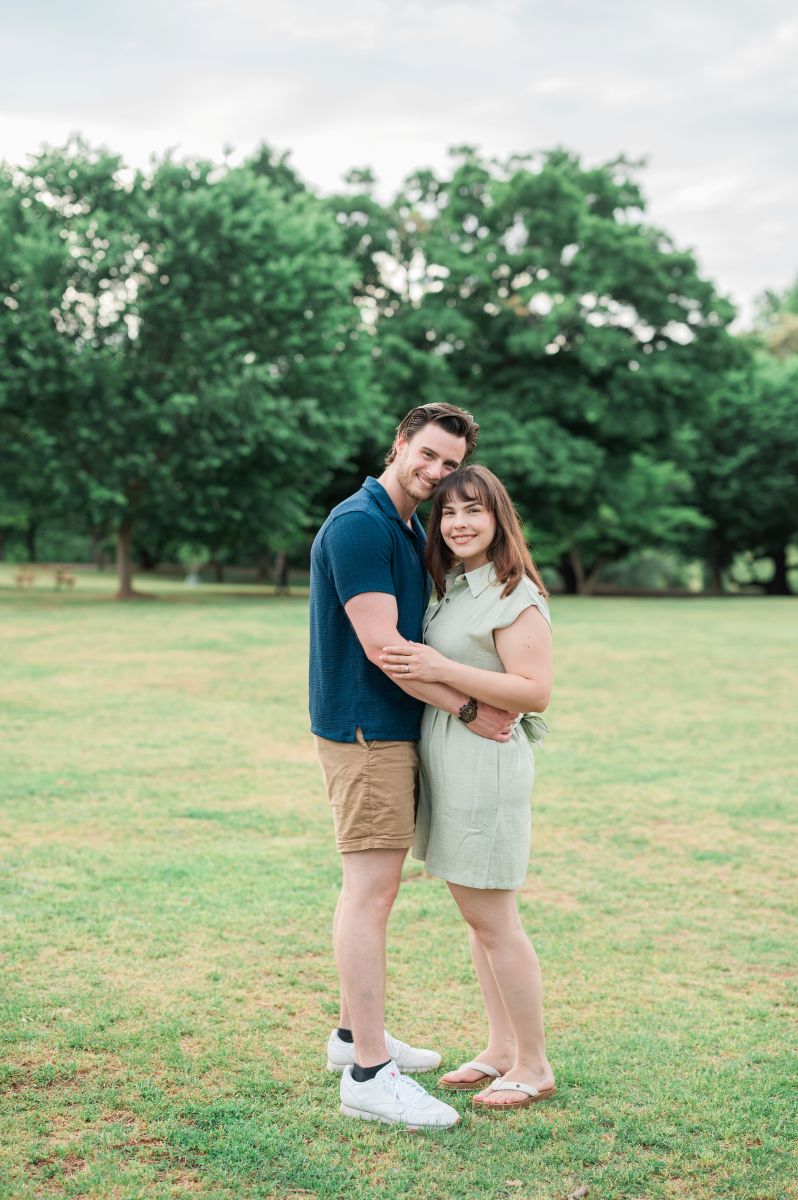 a couple hugging each other on a lawn and smiling