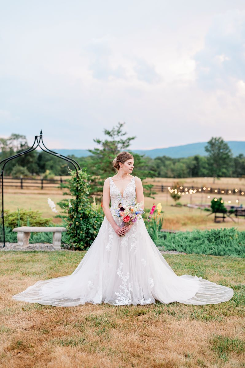a woman wearing a white wedding dress posing at puesta del sol farm next to her wedding ceremony site