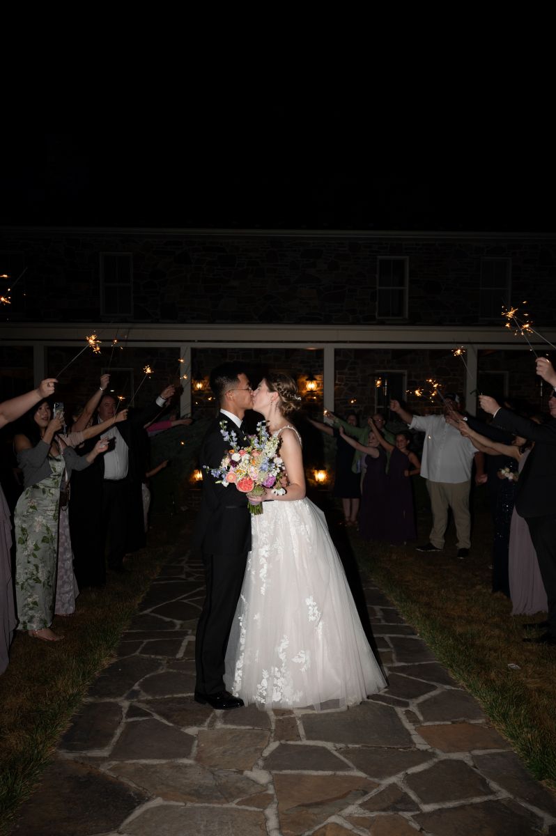a couple having their wedding exit at puesta del sol farm in viriginia their guests are holding up sparklers
