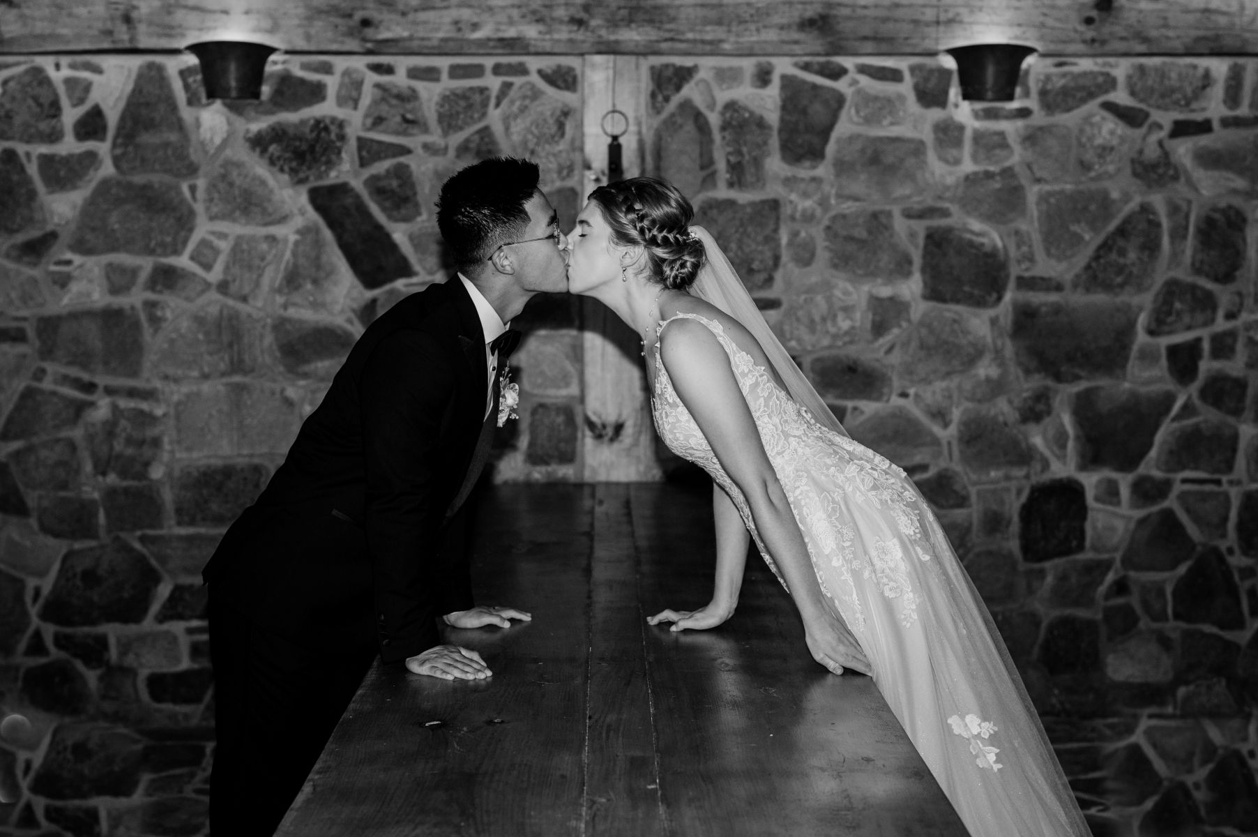 a copule kissing in a wine cellar the woman is wearing a white wedding dress and veil and the man is wearing a black suit